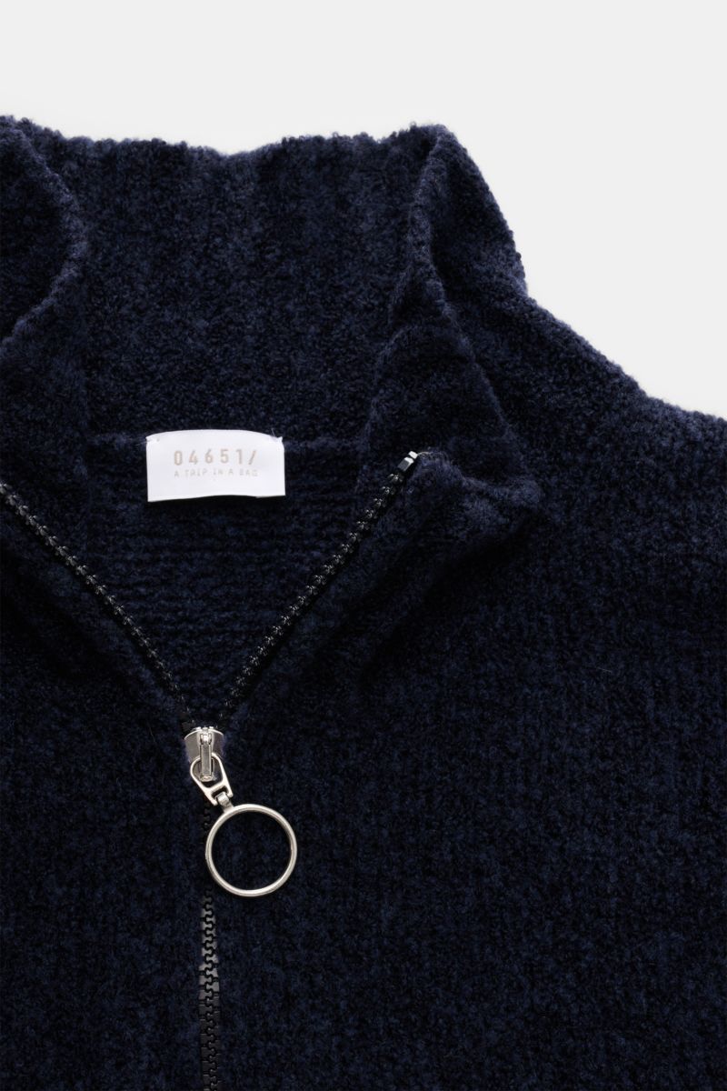 Nahaufnahme aus schräger Perspektive eines navyfarbenen Troyers 04651/ A trip in a bag Troyer 'Grainy' navy mit hohem Rippstrickkragen, Zipper, breiten Rippbündchen, mittelfeinem Boucléstrick aus Wolle und Microfaser, Regular Fit, weicher Griff.