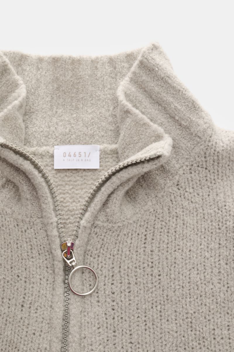 Nahaufnahme aus schräger Vogelperspektive eines Troyers 04651/ A trip in a bag Troyer 'Grainy' sand aus Boucléstrick, Mix aus Wolle und Microfaser, weicher Griff, mittelfeines Strickbild, Regular Fit, hoher Rippstrickkragen mit Zipper und breiten Rippbünd