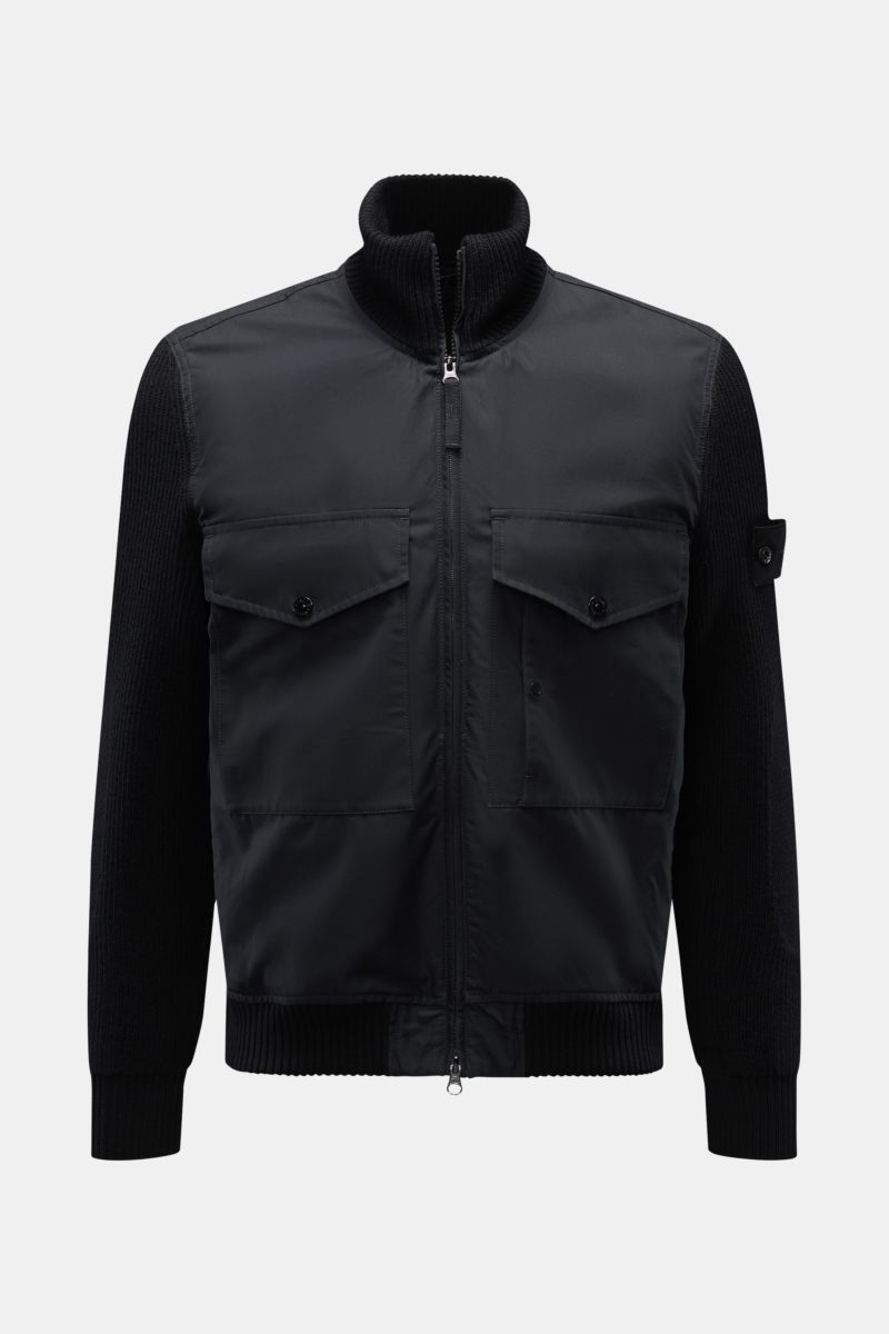 Stone Island Blouson 'Ghost Piece' schwarz, frontal fotografiert, mit Baumwoll-Corpus, Woll-Strickärmeln, zwei Fronttaschen, hohem Kragen und tonalem Badge.