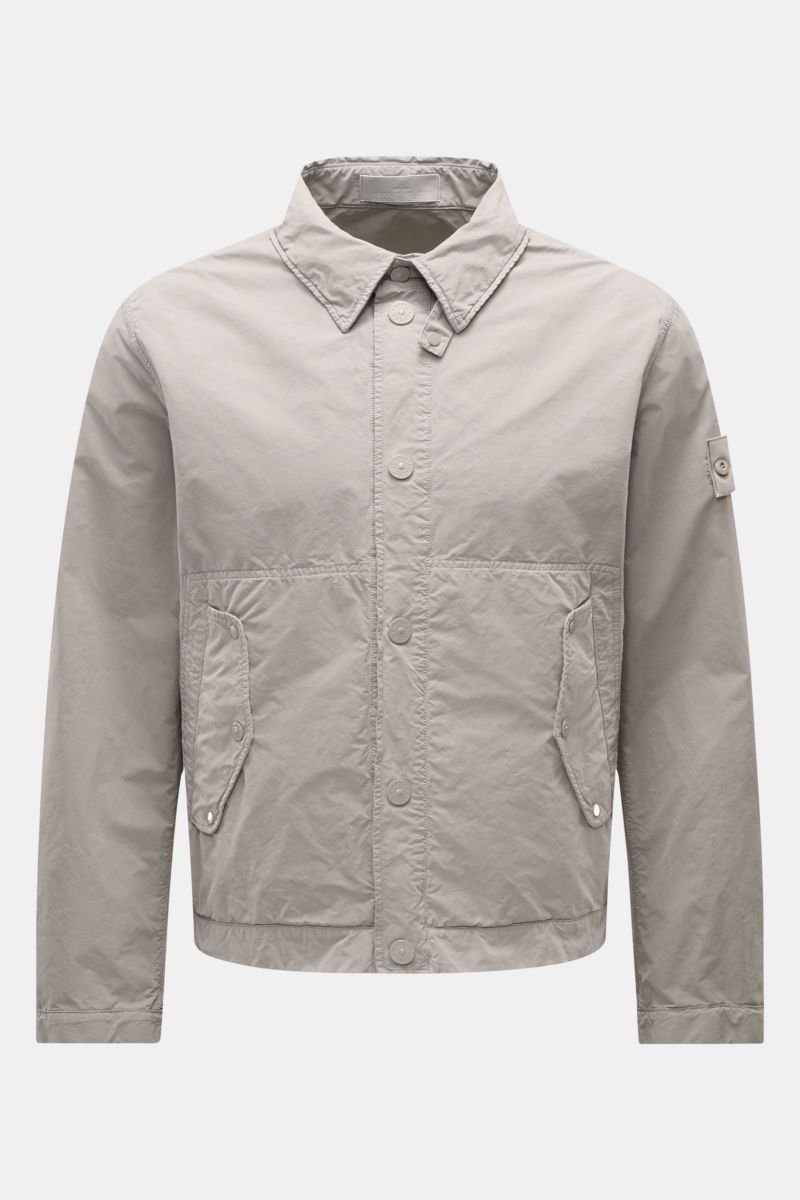 Front view of Stone Island Jacket 'Ghost Piece' light grey, slim fit with snap button placket, turn-down collar, flap pockets, and tonal compass badge, made of high-quality microfibre with a soft feel. Urban essential for any occasion.