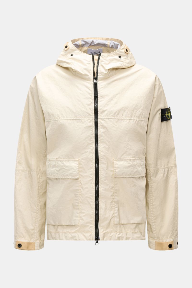 Front view of Stone Island Jacket 'Membrana' cream with hood, two patch pockets, two-way zip, buttoned cuffs, and compass badge on sleeve. Function meets style: The triple-layer functional fabric of this STONE ISLAND jacket is laminated with a breathable,