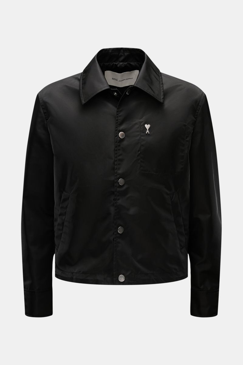 Front view of Ami Paris Jacke schwarz in black microfiber with regular fit, smooth texture, snap button placket, turn-down collar, logo on chest, piped front pockets with snaps, button cuffs, adjustable hem, unconstructed design, and one inside pocket.