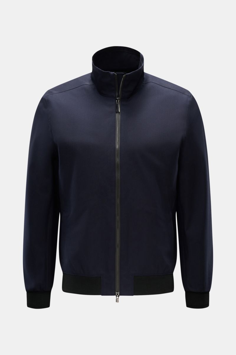 Front view of UBR Blouson 'Bullet Savile' navy, a slim fit, minimalist and functional jacket with fine wool fabric, standing collar, two-way zip, side zip pockets, flexible knit bands, and one inside pocket. Wind and water repellent with sealed seams, mad