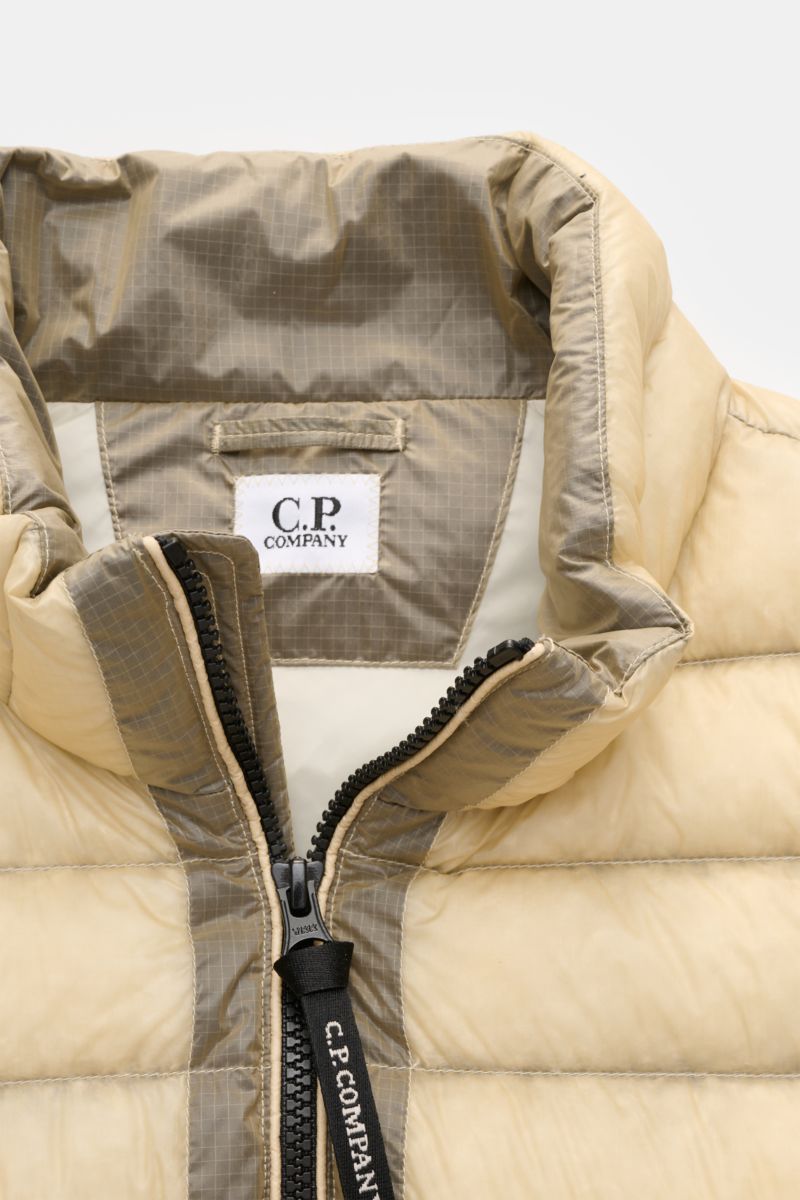 C.P. Company Daunenweste 'D.D. Shell' beige shown from a close-up front perspective, highlighting the padded collar, black two-way zipper with branded pull, and smooth ripstop microfiber fabric. The down vest is crafted with superfine, water-repellent mat