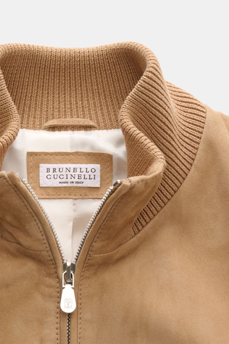 Close-up front view of the Brunello Cucinelli Outdoorweste camel, featuring a high ribbed stand collar, two-way zipper, and soft suede velour leather. Edles Übergangs-Essential: Die Velourslederweste von BRUNELLO CUCINELLI verleiht Outdoor-Looks eine luxu