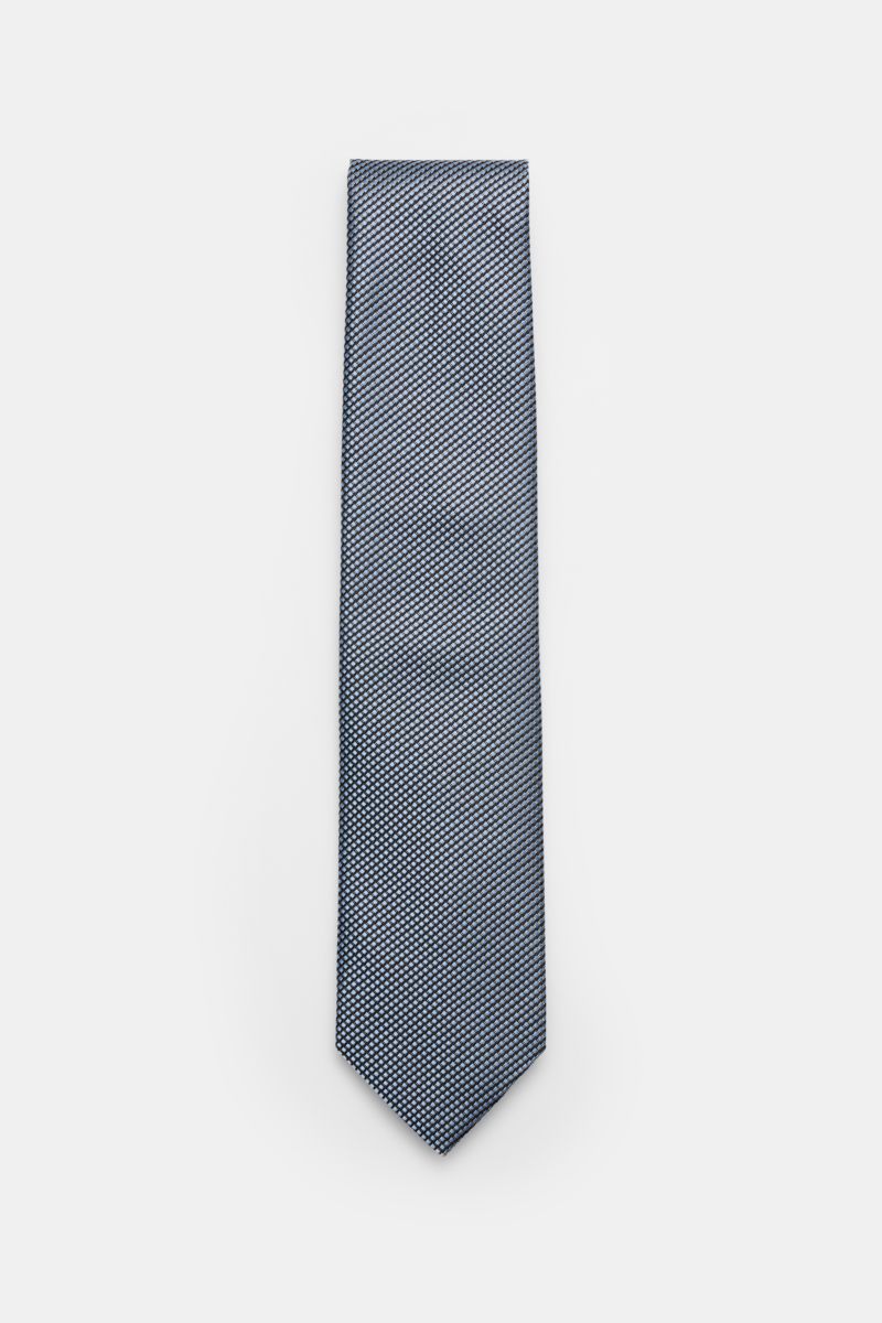 Front view of the Tom Ford Seidenkrawatte hellblau/schwarz/grau gemustert, a light blue, black, and gray silk tie with a fine graphic weave and subtle sheen.

Italienische Handwerkskunst: Dieser Krawatten-Klassiker von TOM FORD aus reiner Seide vereint