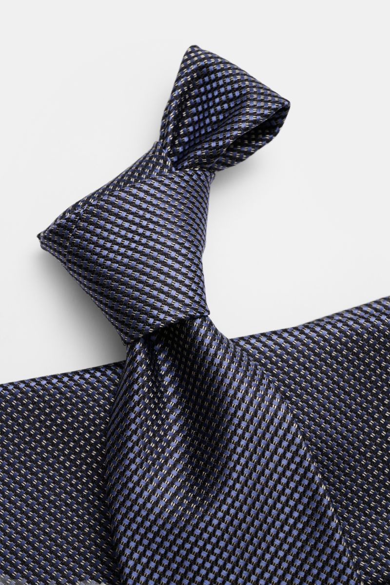 Close-up front view of Tom Ford Seidenkrawatte rauchblau/schwarz/grau gemustert silk tie with subtle sheen and fine geometric pattern.

Italienische Handwerkskunst: Dieser Krawatten-Klassiker von TOM FORD aus reiner Seide vereint zeitlose Eleganz mit e