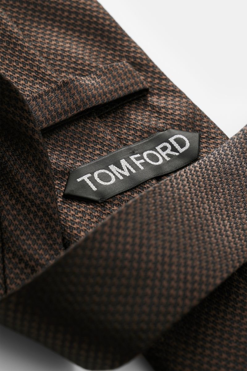 Tom Ford Seidenkrawatte dunkelbraun/schwarz gemustert, Hahnentritt, dezenter Glanz, Logo-Stitching, reine Seide, Detailfoto aus schräger Nahaufnahme.