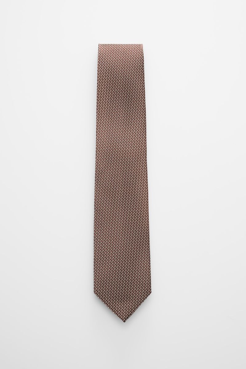 Tom Ford Seidenkrawatte braun/creme gemustert, aus reiner Seide, mit dezentem Glanz und Logo-Stitching, perspektivisch von oben fotografiert.