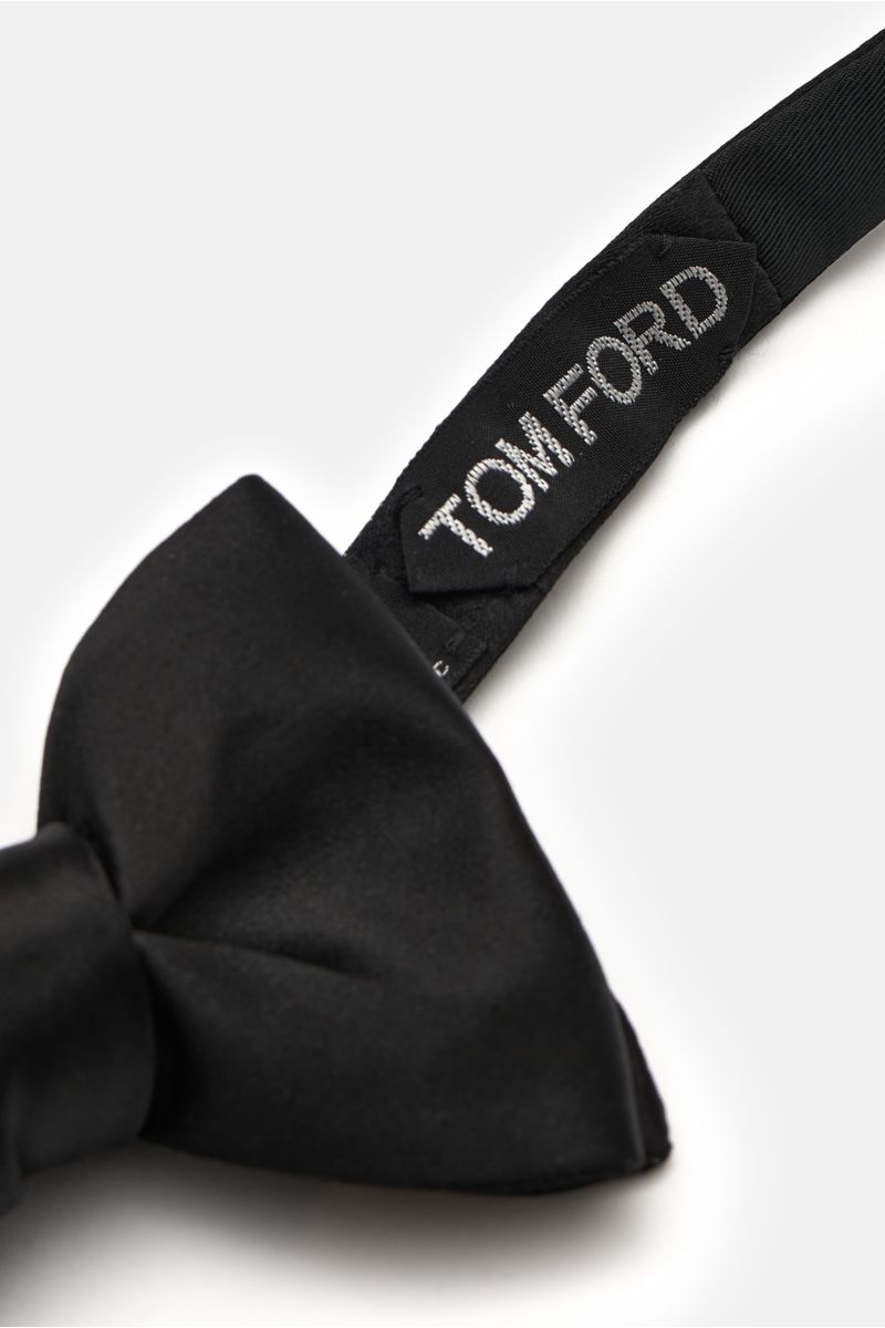 Front close-up of a Tom Ford Seidenschleife schwarz, an elegant black silk satin bow tie with slight sheen, tied style, approx. 10.5 cm wide, showing the stitched Tom Ford label on the strap.

Diese elegante gebundene Schleife von TOM FORD besteht aus 