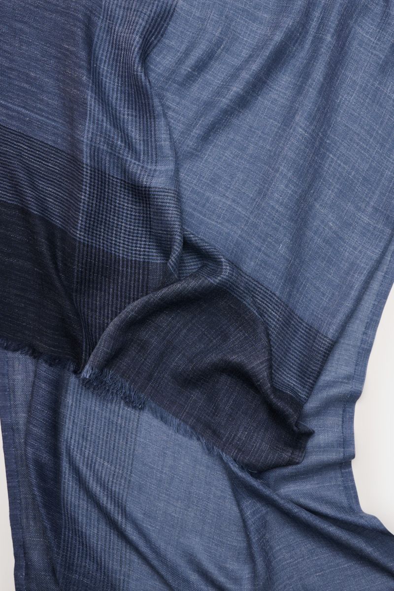 Close-up top view of the Brunello Cucinelli Schal graublau/navy kariert showing its soft silk and linen blend with a subtle plaid pattern and narrow fringed edges.

Additional description: 
Das Quiet-Luxury-Label BRUNELLO CUCINELLI ist bekannt für sein