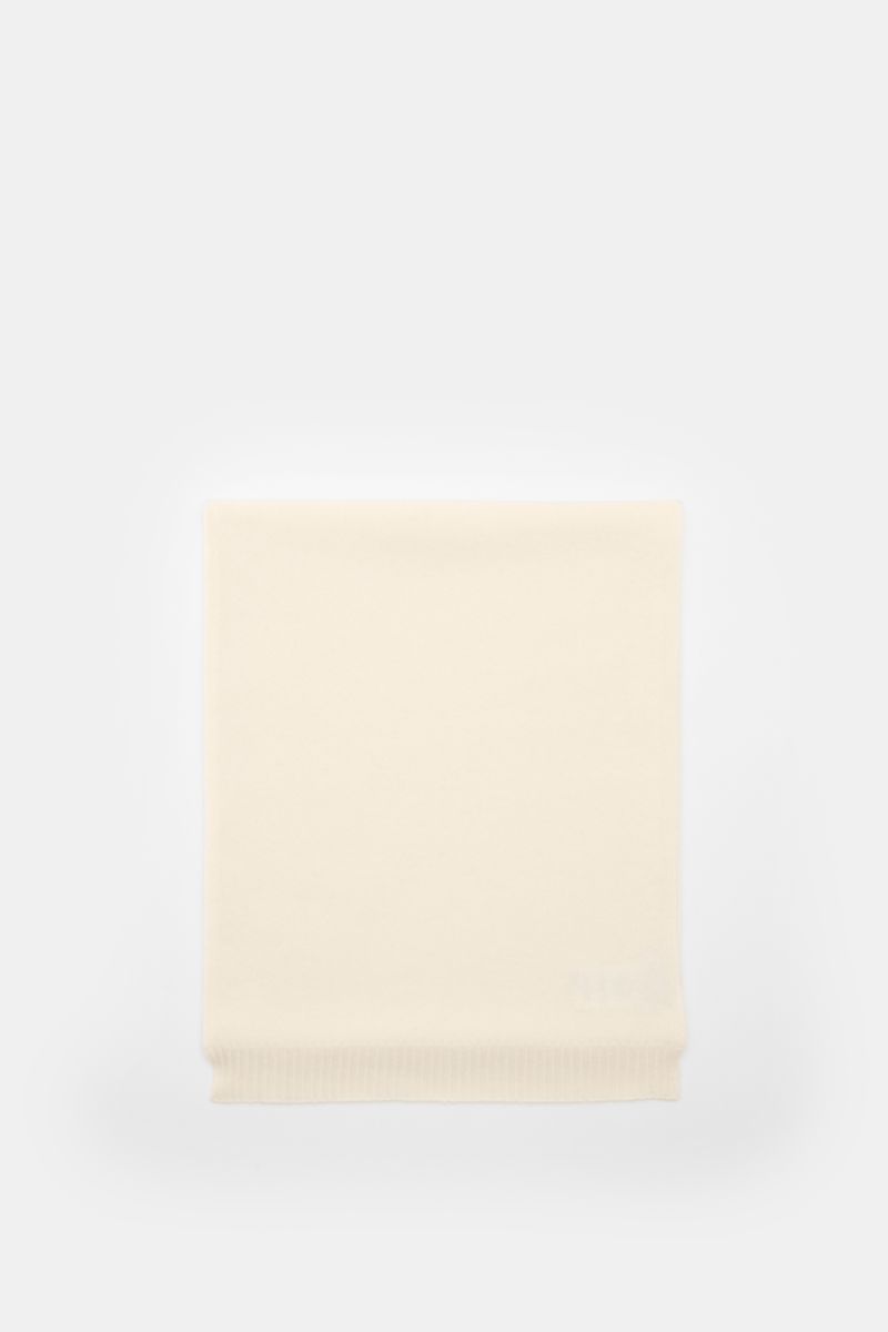 Top-down view of the 04651/ A trip in a bag Cashmere Schal creme, a luxurious cream-colored cashmere scarf with ribbed edges, measuring approximately 162 cm x 34 cm, soft to the touch and part of the 'Look of the Games' Capsule inspired by the 2026 Olympi