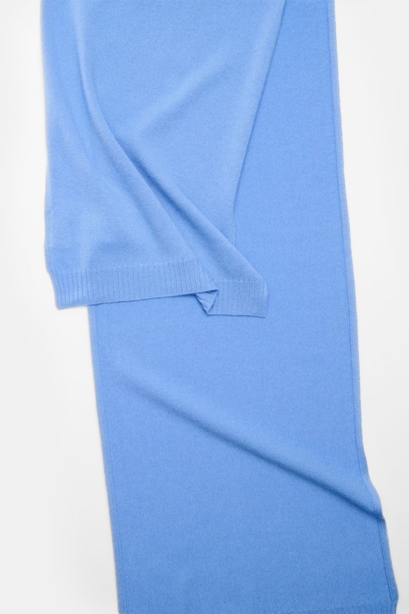 Top-down view of the 04651/ A trip in a bag Cashmere Schal blau, a luxurious soft blue pure cashmere scarf with rib-knit edges, measuring approx. 162 cm x 34 cm.

Edle Wärme für die kalte Saison: Der luxuriöse Cashmere-Schal aus der 'Look of