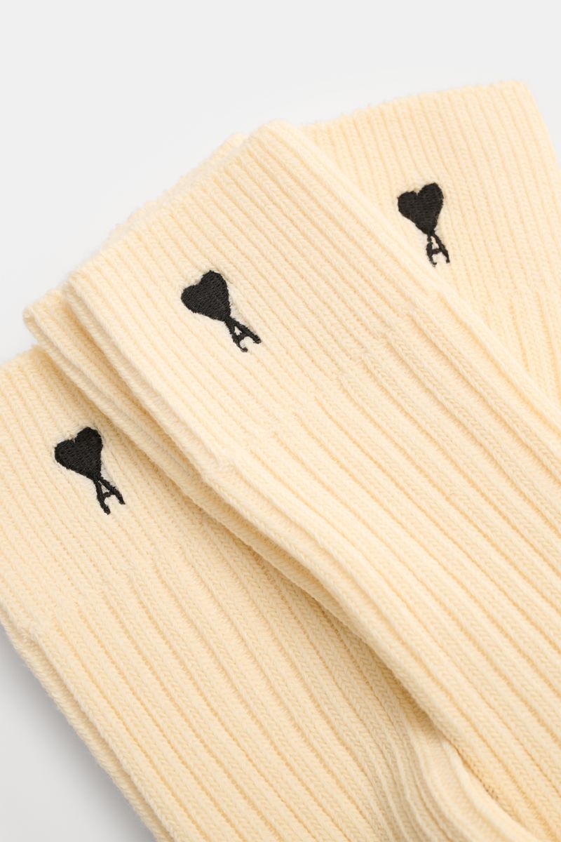 Close-up top-down view of Ami Paris Socks pack of 3 pairs cream, rib knit with signature black heart stitching on cuff.

French label AMI PARIS has added its signature stitching to transform this pack of 3 pairs of socks from a basic to a passionate st