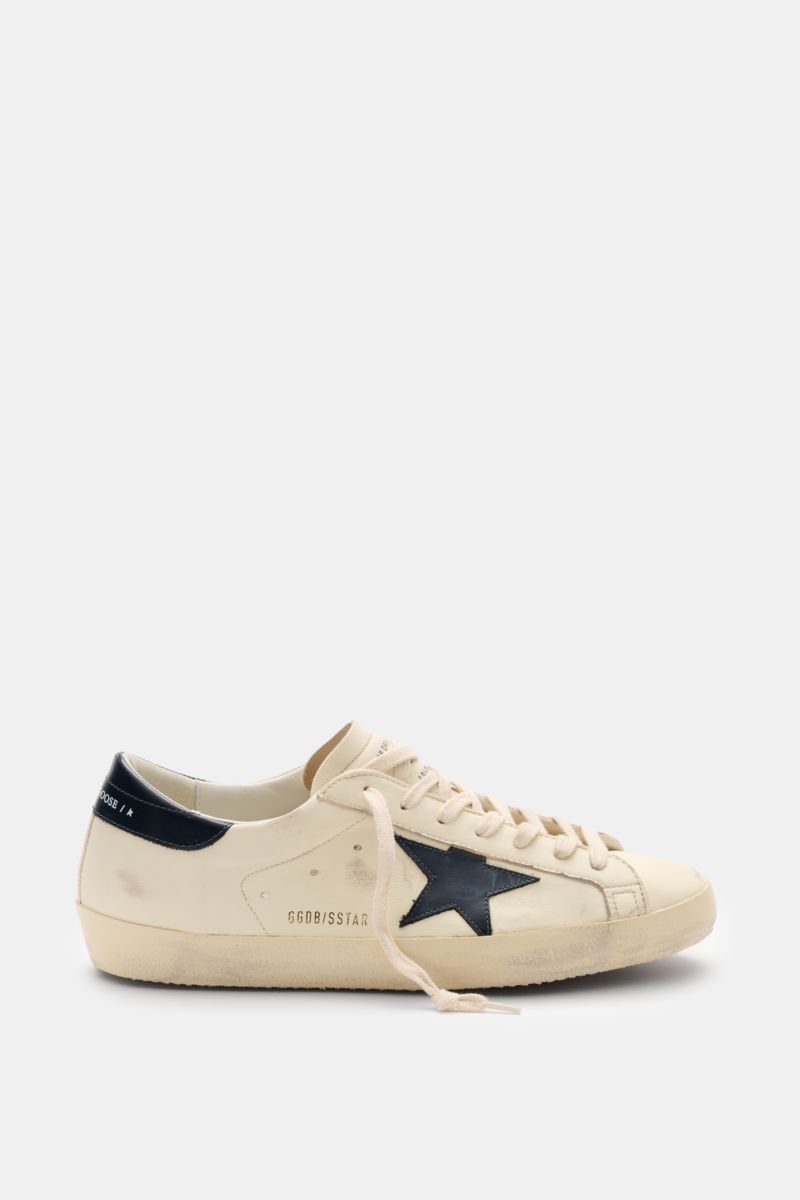 Golden Goose Sneaker 'Super-Star Classic' creme/navy shown from the side with vintage-finish, iconic navy star, hand-made used look, and creme laces. Für alle, die Patina feiern statt Perfektion: Der 'Super-Star Classic' bringt mit Vintage-Finish, dem 