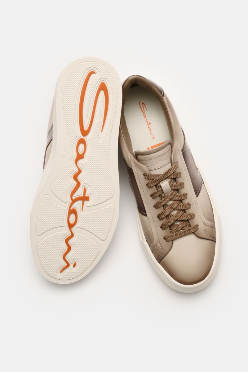 Santoni Sneaker 'Double Buckle' taupe shown from above with one shoe sole up, featuring fine leather, double buckle overlay, round shape, seven-eyelet lacing, emblem on tongue, padded collar, leather lining, flexible rubber sole; homage to classic monkstr