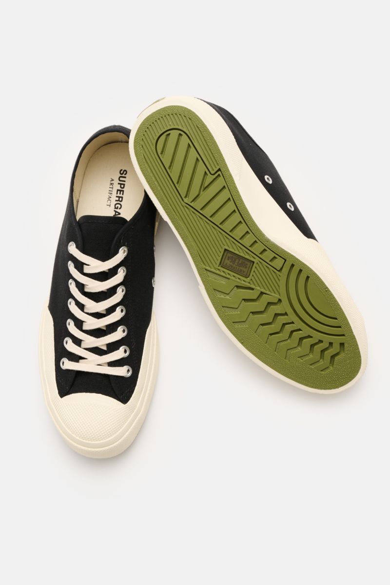 Superga Sneaker 'Works' schwarz/offwhite shown from above with one shoe sole up, inspired by 1970s workwear, robust cotton canvas, seven-eyelet lacing, cotton lining, flexible green rubber sole.