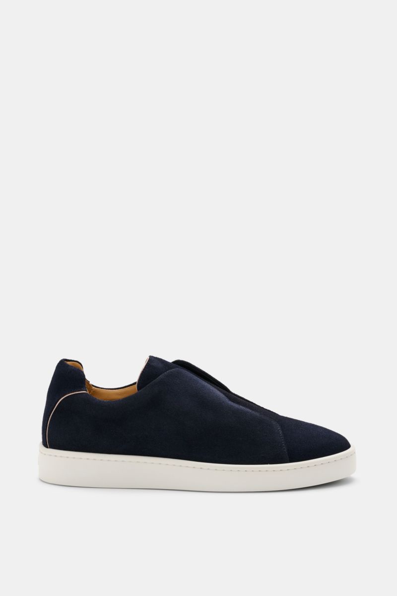 Side view of the Aurélien Slip-on-Sneaker navy in soft veloursleder with a round toe, elastic bands inside, padded collar, subtle logo embossing, leather lining, and flexible white rubber sole, showcasing its clean, monochrome design for full comfort.