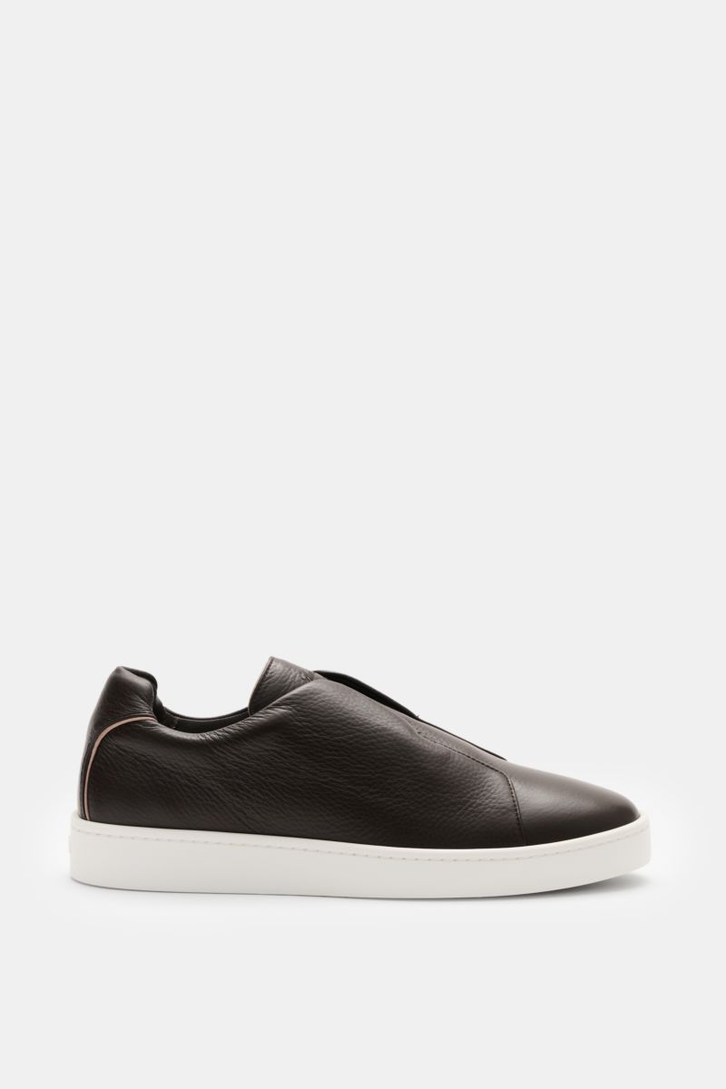 Side view of Aurélien Slip-on-Sneaker dunkelbraun in finely grained dark brown leather with round toe, elastic bands, padded collar, subtle logo, leather lining, and flexible white rubber sole, showcasing minimalist design and craftsmanship.