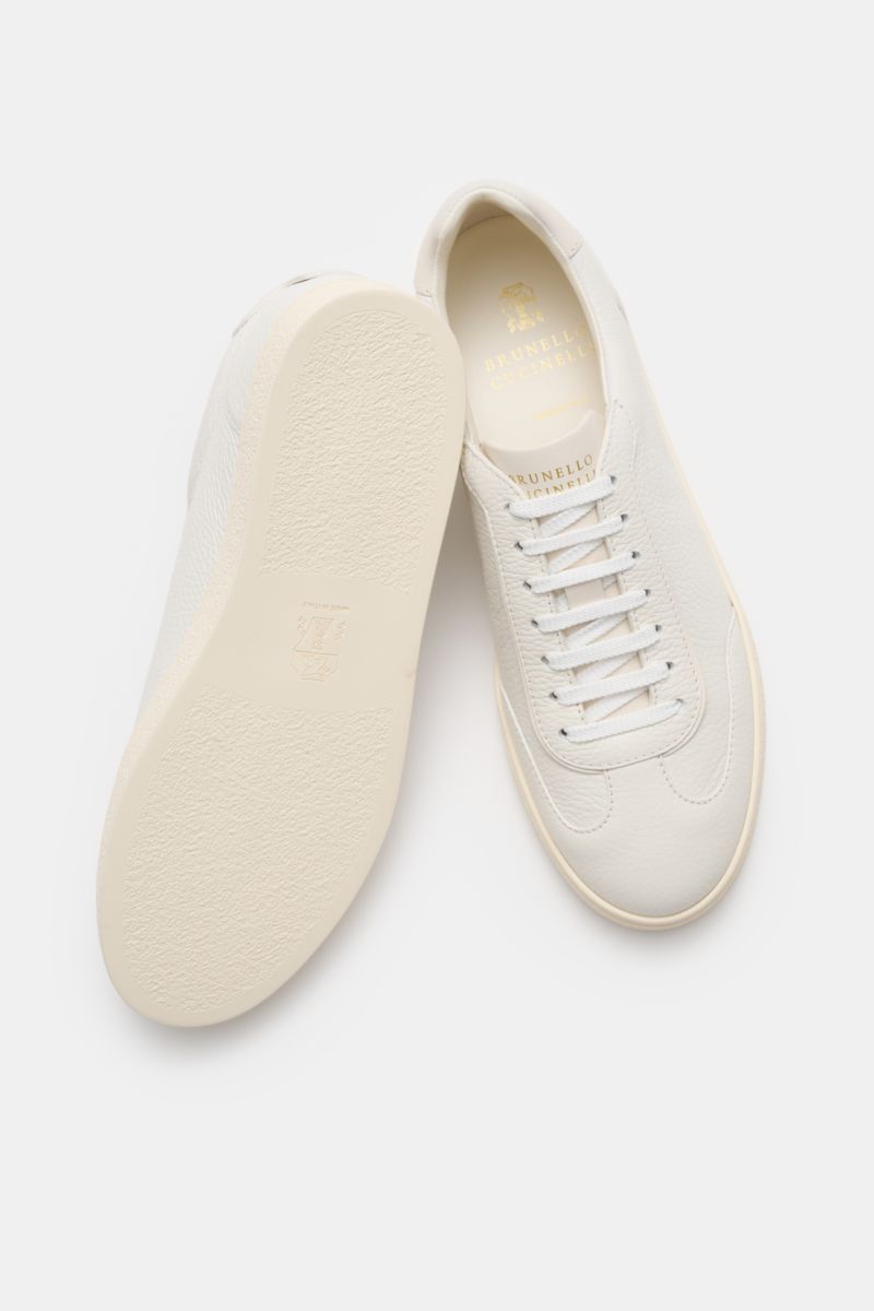 Brunello Cucinelli Sneaker creme aus geschmeidigem Leder, von oben fotografiert, mit schmaler Silhouette, Flügelkappe, goldener Prägung.