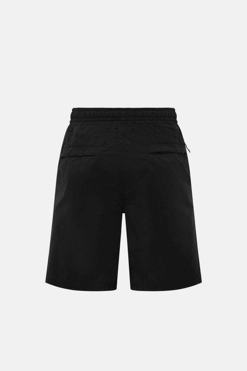 Rear view of Stone Island Swim shorts 'Ghost Piece' black, featuring high-quality microfibre, elastic waistband, zipped side and back pockets, mesh lining, and a monochrome woven label at the hem for a sporty, innovative look. 

Description:  
A monoch