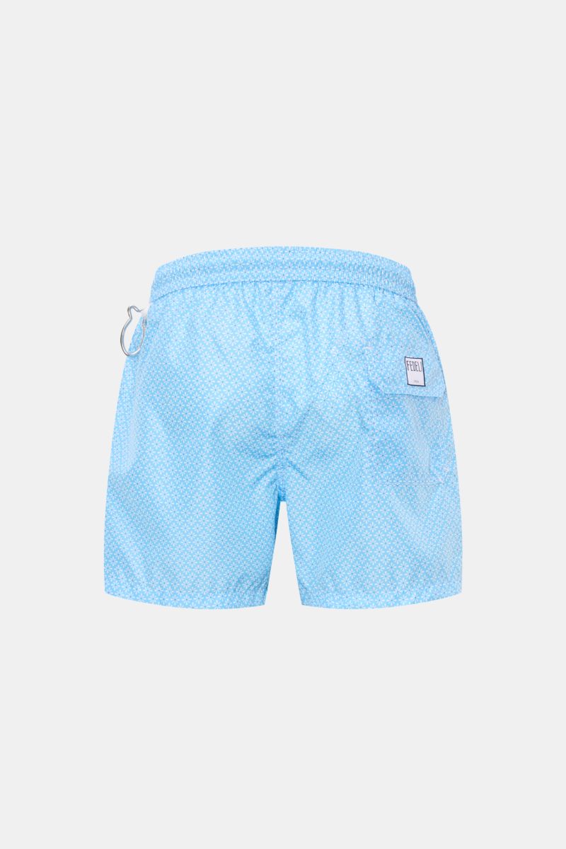 Back view of Fedeli Swim shorts 'Madeira Airstop' light blue/white patterned with floral design, elastic waistband, side and back pockets, and whale-shaped carabiner.

Description: 
An essential for your summer vacation: These FEDELI swim shorts have a