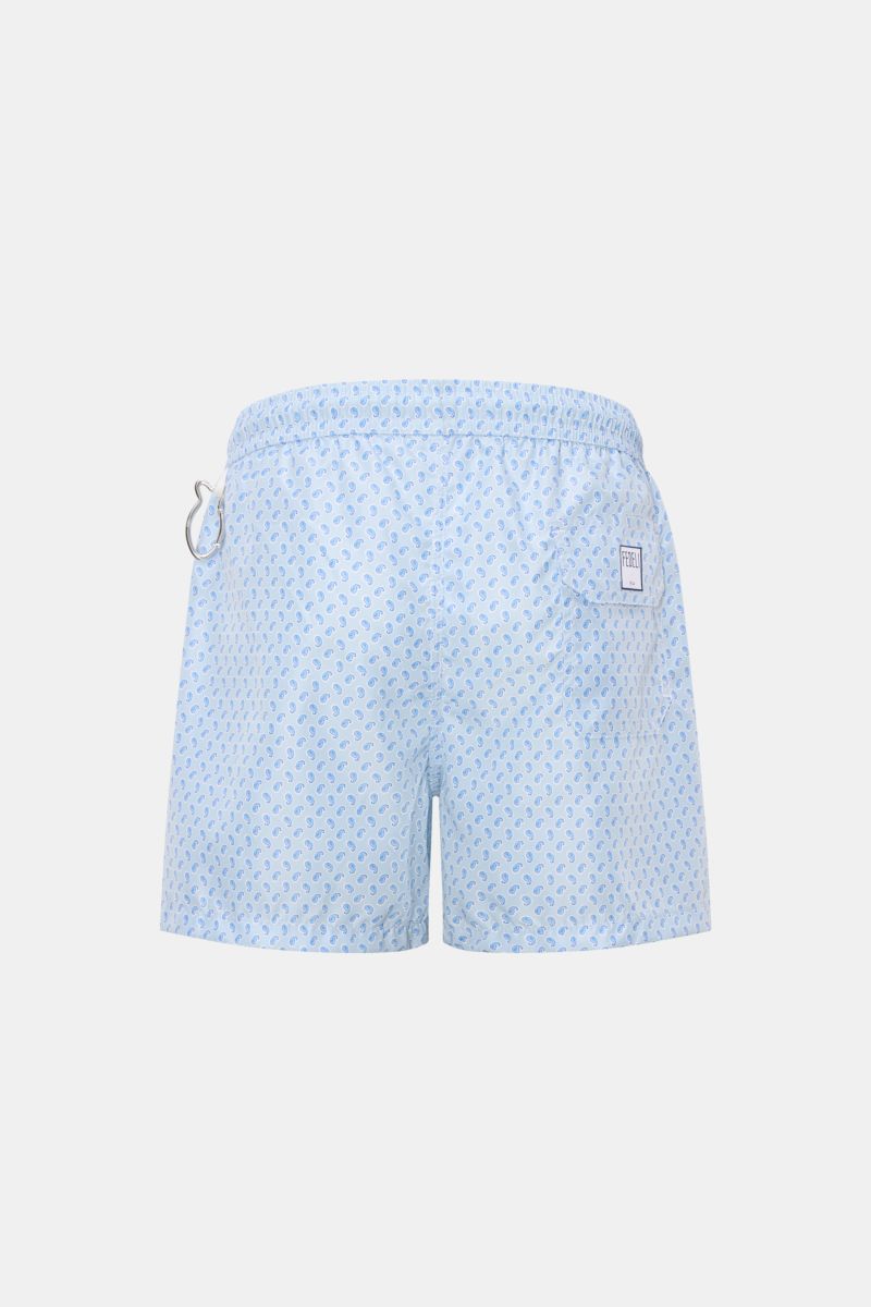 Back view of Fedeli Swim shorts 'Madeira Airstop' light blue/white/blue patterned with paisley design, elasticated waistband, and whale-shaped carabiner.

An essential for your summer vacation: These FEDELI swim shorts have an expressive pattern that a
