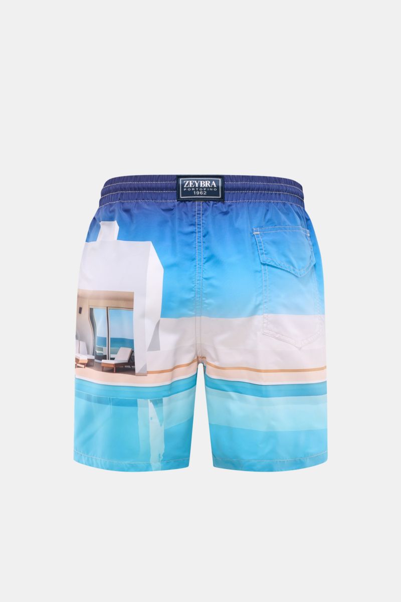 Rear view of Zeybra Portofino 1962 Badeshorts 'Villa' blau/offwhite/türkis with elastic waistband and side seam pockets, featuring a vibrant allover print of a modern villa by the pool. Sommerliches Statement: Mit ihrem markanten Allover-Print werden d