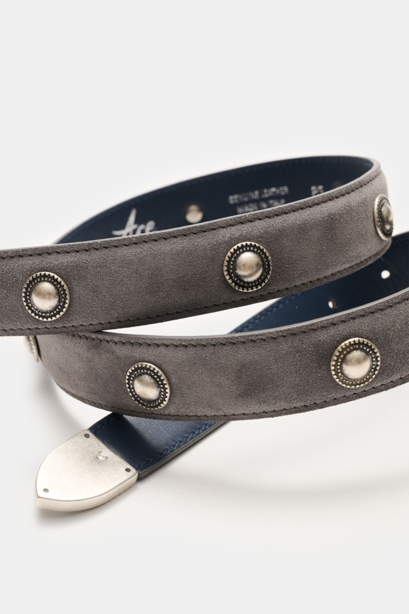 Ace Denim Veloursleder Gürtel 'Cowboy Belt' grau shown from a close-up side angle, soft grey suede with silver Western-style conchos, decorative metal tip, and silver buckle.