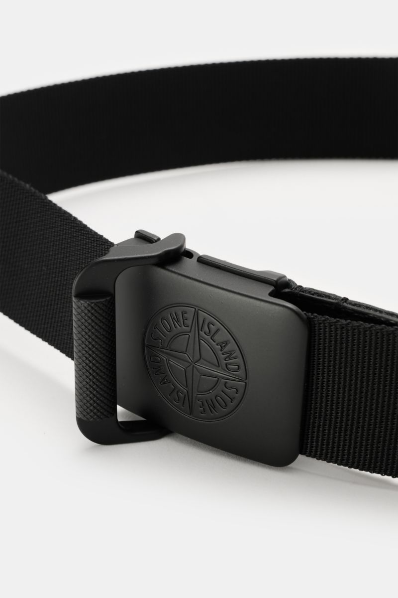 Close-up front view of Stone Island Gürtel schwarz with matte black rubberized metal buckle featuring iconic compass logo, made of high-quality microfiber, adjustable, 4 cm wide, made in Italy. Dieser gewebte Gürtel von STONE ISLAND ist mit seiner gumm