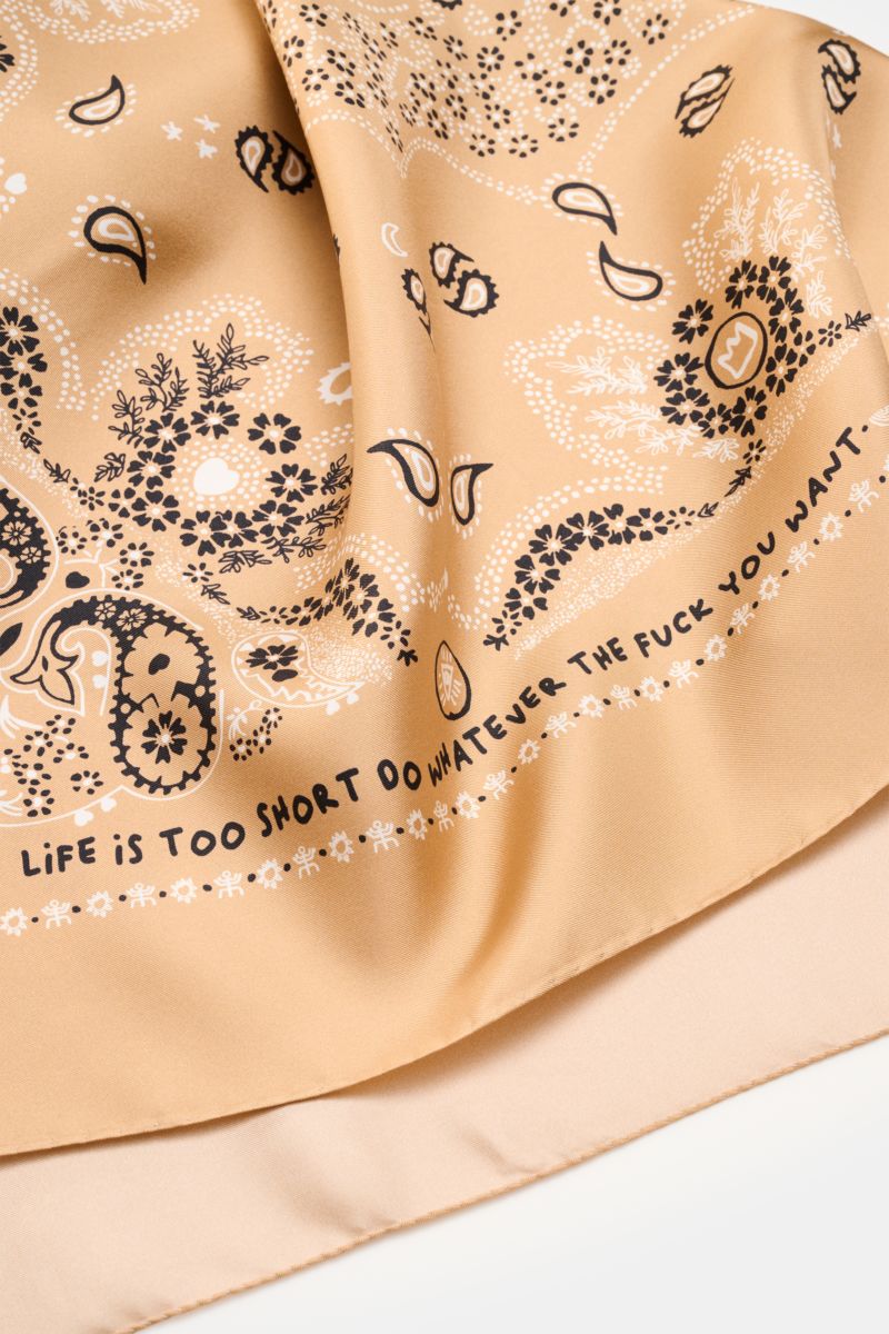 Close-up front view of the Ace Denim Silk scarf light brown/black/white patterned with paisley design, soft pure silk fabric.

Eye-catching for the warm season: The ACE DENIM silk scarf in a bandana design is a casual statement accessory for summer loo