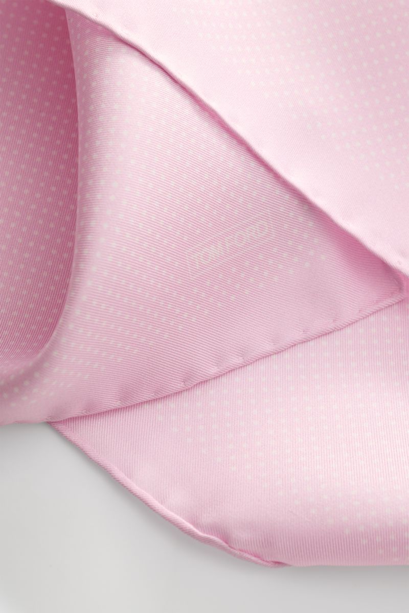 Tom Ford Seiden-Einstecktuch rosé/weiß gepunktet shown close-up from an angled perspective, highlighting its pure silk fabric, smooth texture, subtle polka dot pattern, rolled edges, and small TOM FORD print. Dieses Einstecktuch von TOM FORD aus reiner