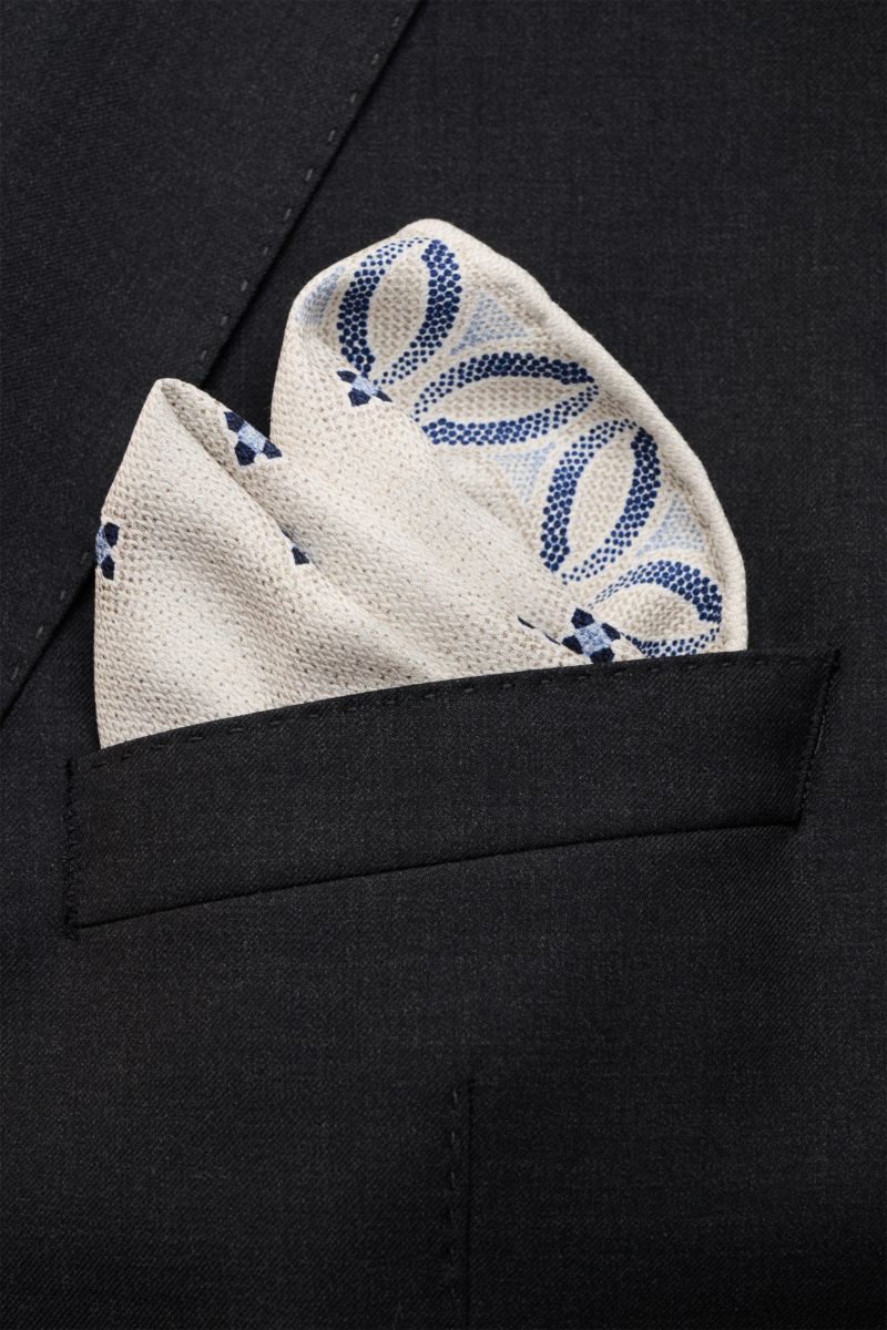 Brunello Cucinelli Seiden-Einstecktuch creme/sand/dunkelblau gemustert, floral, reine Seide, geschmeidig, handrollierte Kanten, Made in Italy, ca. 35x35 cm, aus Frontperspektive in Sakko-Tasche gesteckt.
