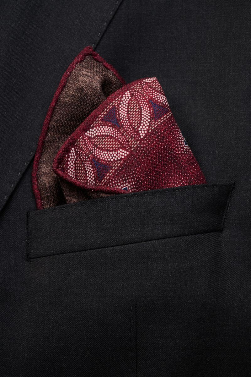 Close-up front view of a Brunello Cucinelli Seiden-Einstecktuch bordeaux/graubraun gemustert pocket square in a black suit jacket pocket, featuring reine Seide, geschmeidiger Griff, floral gemustert, handrollierte Kanten, Made in Italy, Maße: ca. 35 cm x 
