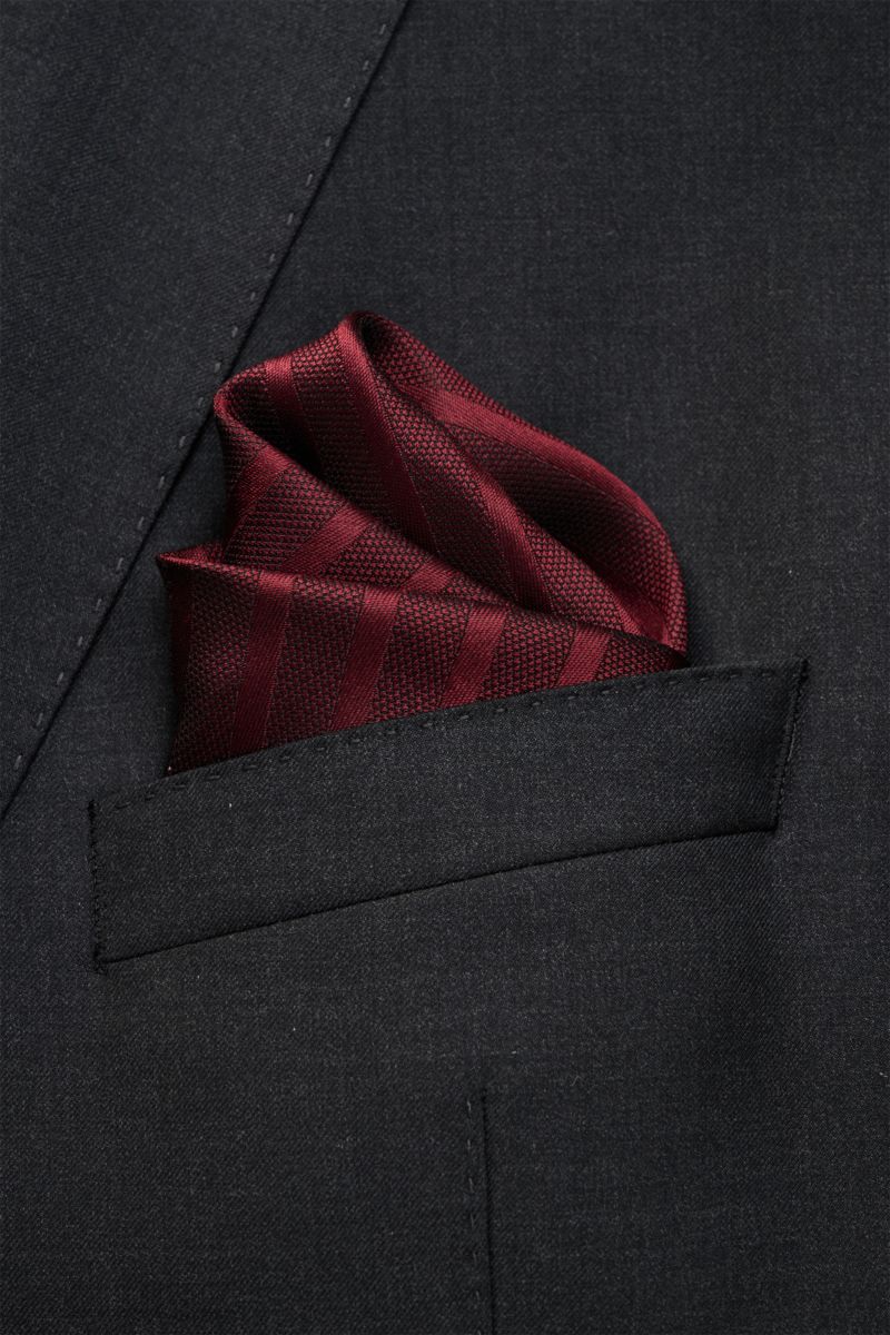 Brunello Cucinelli Seiden-Einstecktuch bordeaux gestreift, reine Seide, geschmeidiger Griff, handrollierte Kanten, Maß ca. 35x35 cm, Made in Italy, von schräg oben fotografiert in dunkler Anzugtasche.