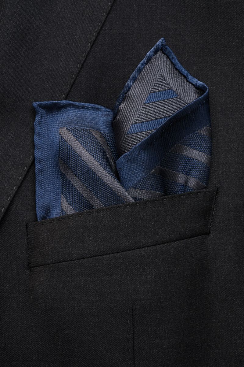 Brunello Cucinelli Seiden-Einstecktuch navy/dunkelgrau gestreift in black jacket pocket, photographed from front close-up view, reine Seide, geschmeidiger Griff, Streifenmuster, handrollierte Kanten, Made in Italy, Maße: ca. 35 cm x 35 cm.