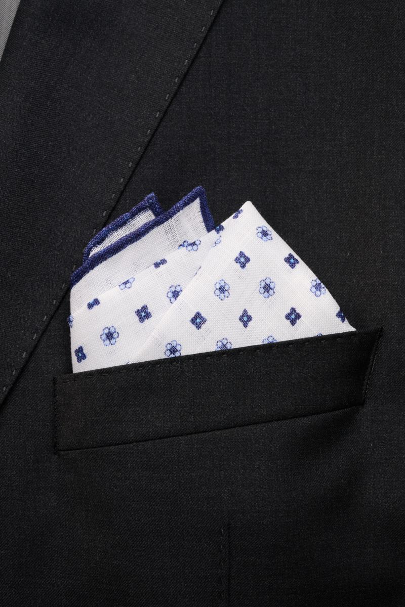 Rosi Collection Linen pocket square 'Fox' white/navy patterned in black jacket pocket, pure linen, soft feel, floral print, rolled edges, made in Italy, 31.5 x 31.5 cm, close-up front view.