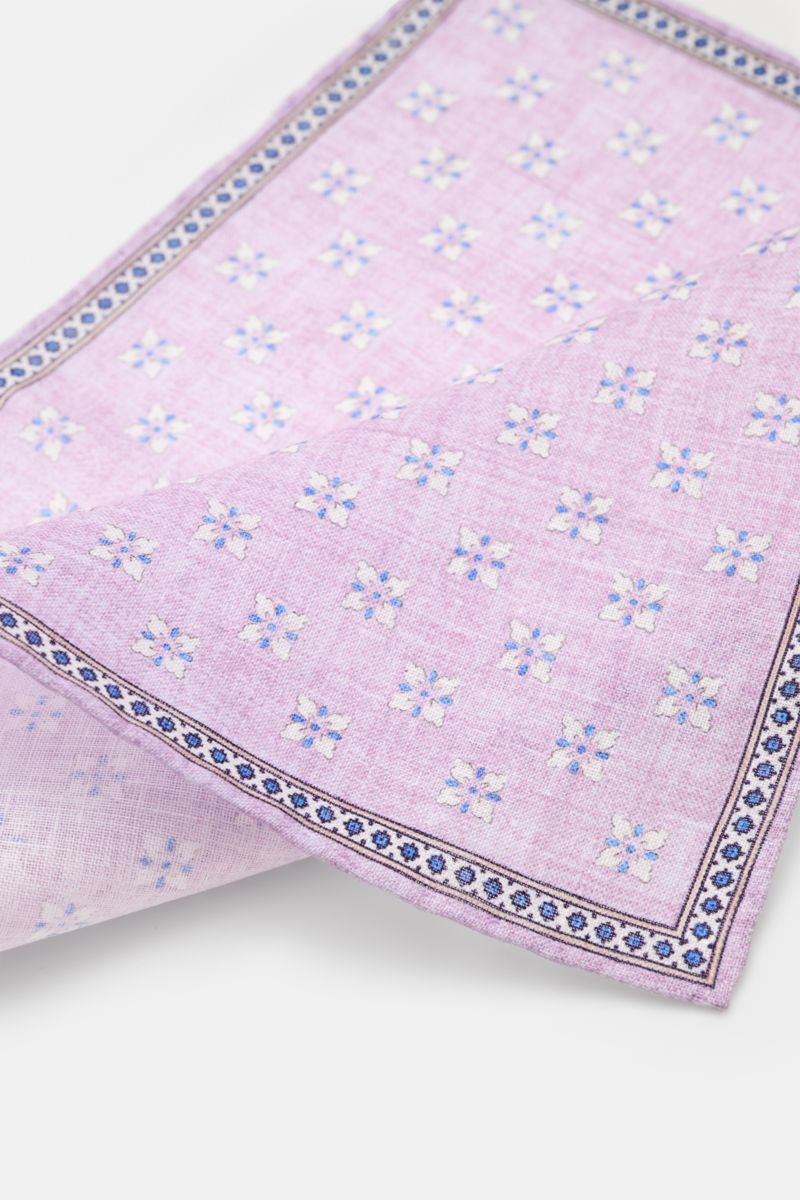 Rosi Collection Linen-pocket square 'Fox' lilac/blue/off-white patterned shown from a top angled view, pure linen, soft feel, floral print with edging, rolled edges, made in Italy, dimensions 31 cm x 31 cm.