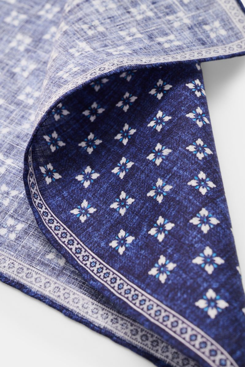 Close-up top-side view of the Rosi Collection Linen pocket square 'Fox' dark blue/light blue/white patterned, showing floral print with edging, rolled edges, pure linen, soft feel, made in Italy, dimensions 31 cm x 31 cm.