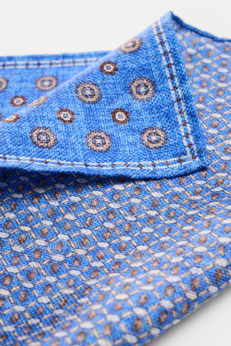 Rosi Collection Einstecktuch 'Joy' blau/weiß/dunkelbraun gemustert, florales Retro-Muster, Seide-Leinen-Mix, rollierte Kanten, doppelseitig, Nahaufnahme schräg von oben.