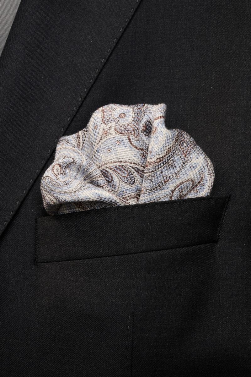 Alt tag (125 characters max): Front view of Rosi Collection Einstecktuch 'Joy' rauchblau/weiß/braun gemustert pocket square in black suit pocket.

Description: 
Eleganter Eyecatcher: Mit seinem modernen Paisley-Muster wird das Einstecktuch von ROSI COL
