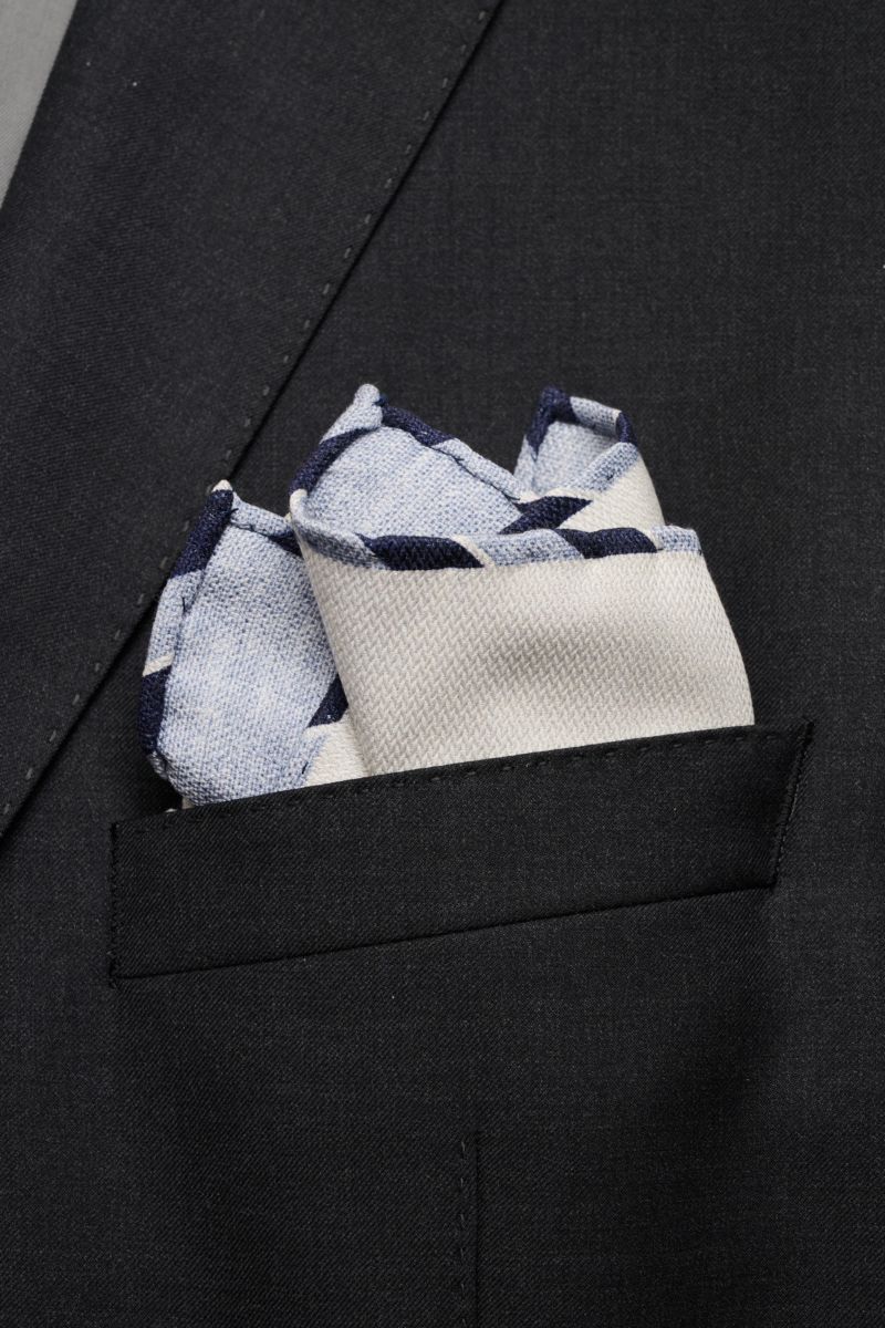 Alt tag (125 characters max):
Close-up from front perspective of Brunello Cucinelli Seiden-Einstecktuch creme/rauchblau meliert in black jacket pocket.

Full description to include:
Quiet Luxury kann BRUNELLO CUCINELLI besonders gut und bringt auch in 