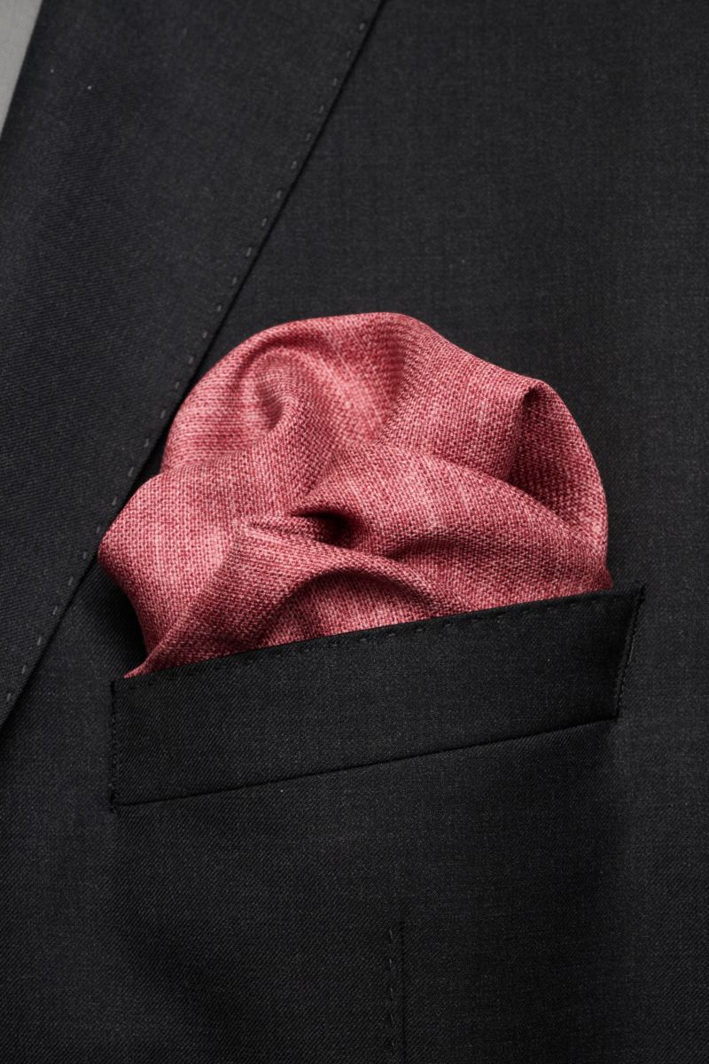 Close-up front perspective of a Brunello Cucinelli Seiden-Einstecktuch dunkelrot/taupe meliert pocket square in a black jacket pocket, showing its textured silk fabric and handrolled edges.

Quiet Luxury kann BRUNELLO CUCINELLI besonders gut und bringt