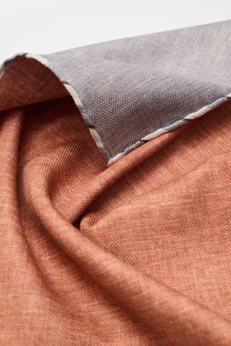Brunello Cucinelli Seiden-Einstecktuch braun/grau meliert shown from a close-up angled perspective, highlighting texture and hand-rolled edges. Quiet Luxury kann BRUNELLO CUCINELLI besonders gut und bringt auch in dieser Saison passende Einstecktücher,