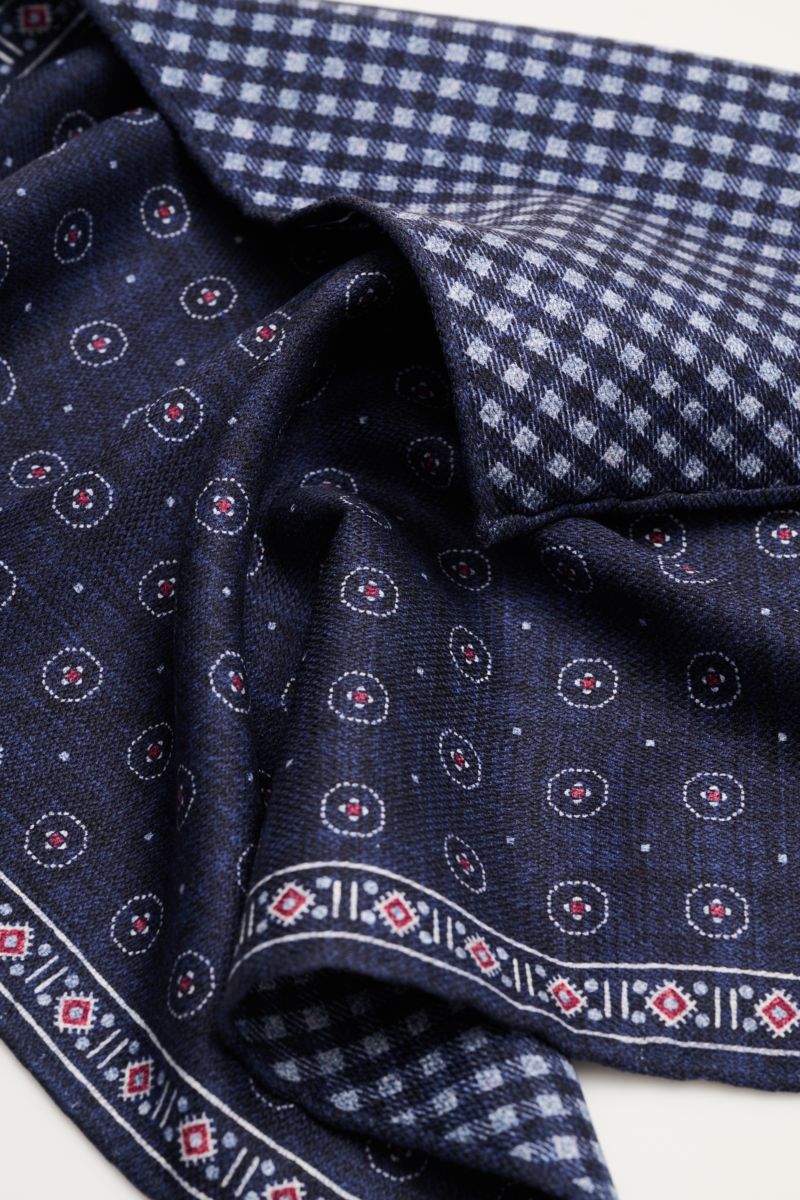 Brunello Cucinelli Seiden-Einstecktuch navy/weiß/rot gemustert shown in close-up from above, highlighting its pure silk fabric with a graphic print and contrasting front and back patterns.

Zeitloser Akzent für besondere Momente: Das Einstecktuch aus r