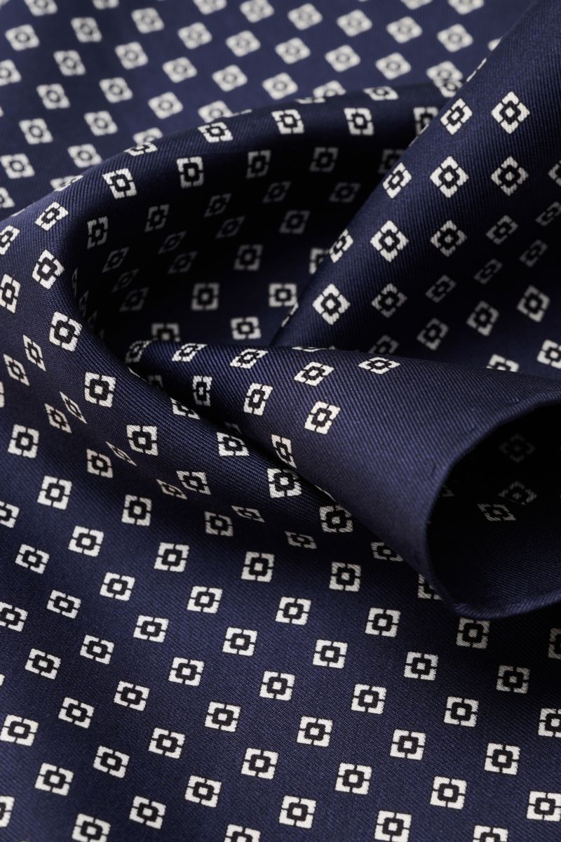Close-up front view of Brunello Cucinelli Seiden-Einstecktuch dunkelblau/schwarz/weiß gemustert with a smooth, glossy silk fabric and graphic pattern.

Quiet Luxury kann BRUNELLO CUCINELLI besonders gut und bringt auch in dieser Saison passende Einstec