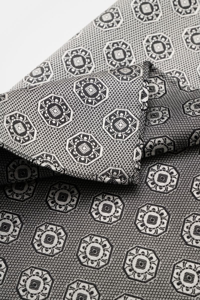 Close-up top view of Brunello Cucinelli Silk pocket square grey/black patterned with medallion weave and rolled edges.

Elegant accent: This silk pocket square by BRUNELLO CUCINELLI has a fine medallion weave pattern that creates a subtle highlight and