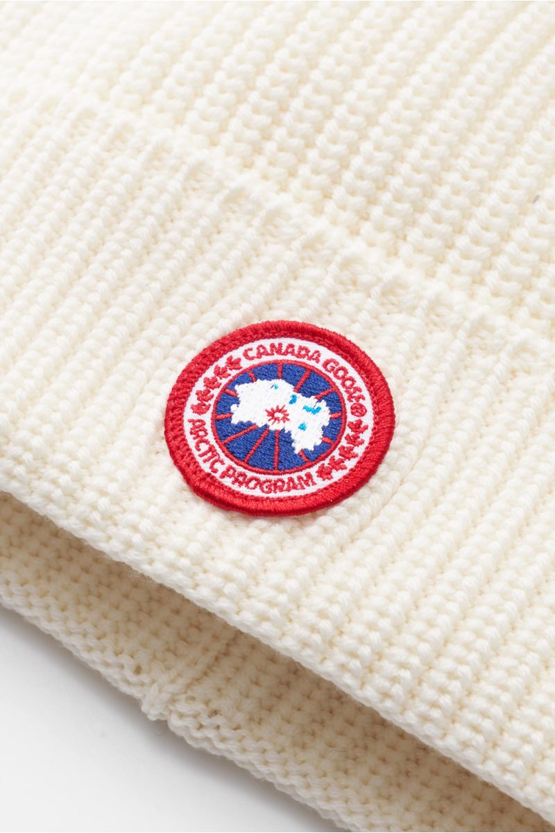 Close-up front-side view of the Canada Goose Wollmütze creme showcasing its pure wool coarse rib knit design with a folded edge and red Canada Goose web label.

Must-Have für die kühle Jahreshälfte: Mit der Mütze aus reinem Woll-Rippstrick vom Outdoor-