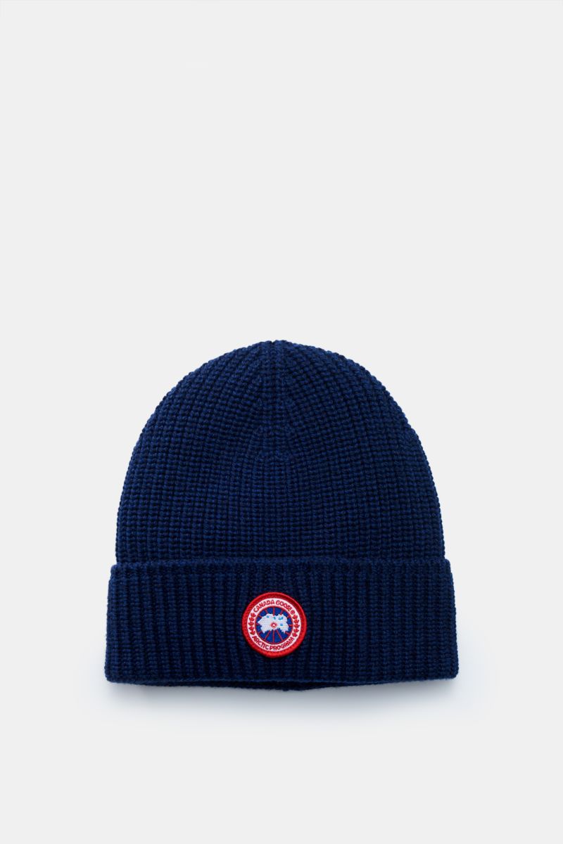 Front view of Canada Goose Wollmütze dunkelblau, a dark blue wool beanie with a chunky ribbed knit, folded cuff, and round red Canada Goose logo patch.

Description: Must-Have für die kühle Jahreshälfte: Mit der Mütze aus reinem Woll-Rippstrick vom Out