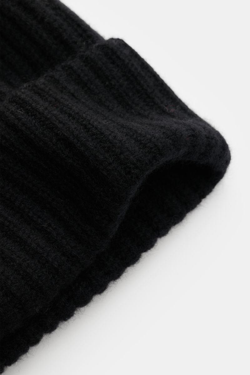 Nahaufnahme der Lisa Yang Cashmere Mütze 'Menton' schwarz, seitlich fotografiert, mit weichem, patentgestricktem Umschlag aus reinem Cashmere.
